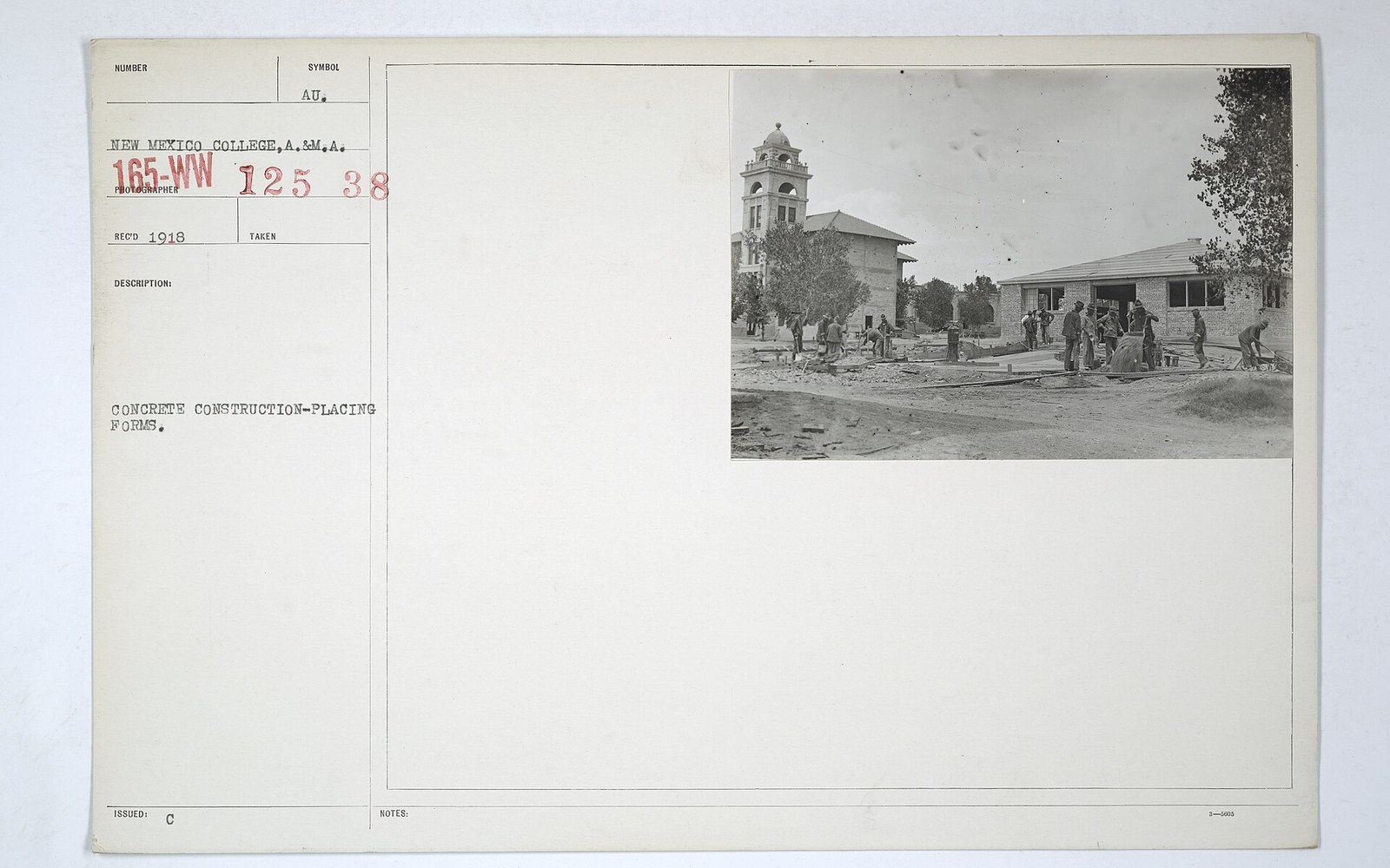 Workers place concrete forms near a tower building on a college campus, archival photo card