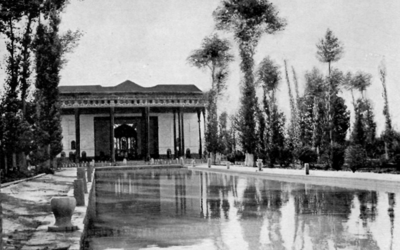 Long reflecting pool leads to a columned pavilion lined with tall cypress trees